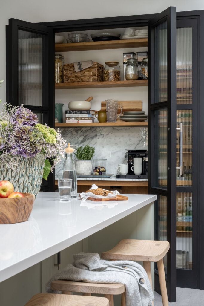 Bespoke pantry larder within a luxury kitchen featuring shelving and reeded glass doors