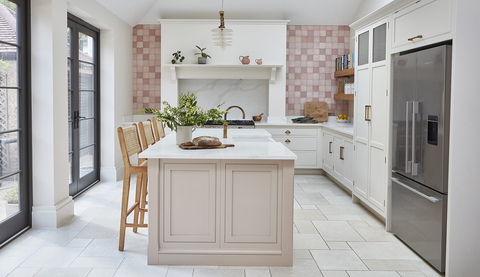 Pink L shaped kitchen with island and white cabinetry featuring luxury design features such as bespoke seating areas and gold hardware