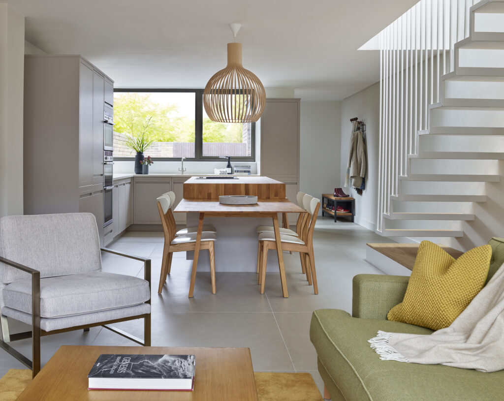 A scandinavian styled kitchen and living area, showcasing an open layout with soft furnishings and oak accents.