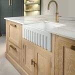 Natural wood Shaker kitchen island with white basin sink, gold tap and stone surface worktop