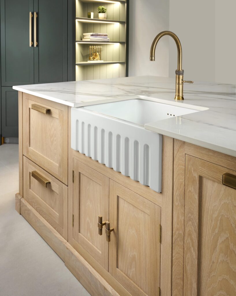Natural wood Shaker kitchen island with white basin sink, gold tap and stone surface worktop