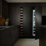 Black Contemporary Harvey Jones kitchen with BORA fridge and walnut wine rack.