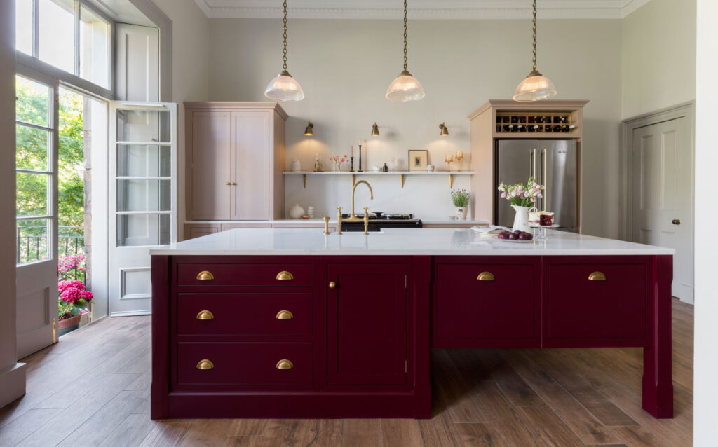 A stylish burgundy kitchen featuring a striking red island complemented by elegant gold hardware accents.