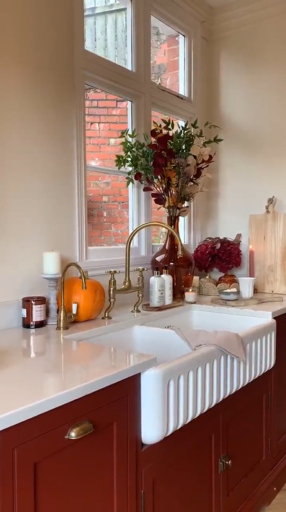 A timeless kitchen with a fluted belfast sink, brass hardware and burgundy red cabinetry.