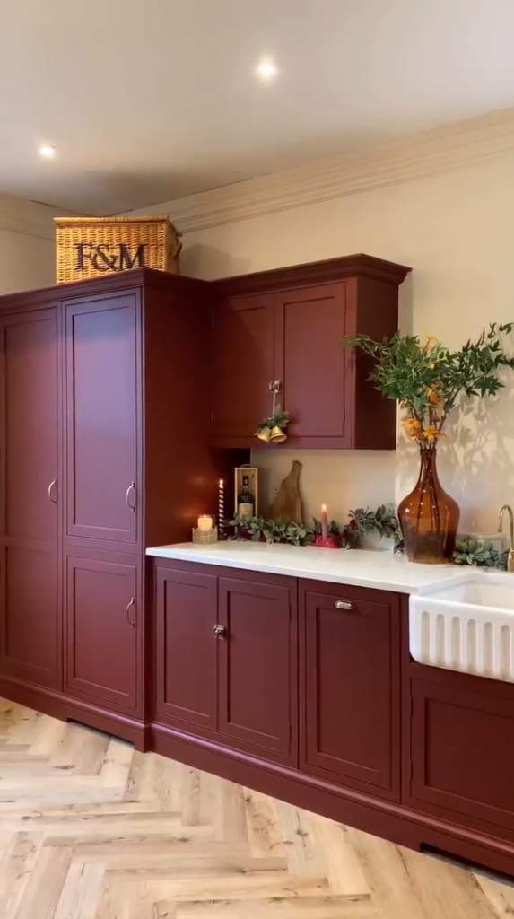 Burgundy red cabinetry and warm wooden floors in a stylish and inviting kitchen.