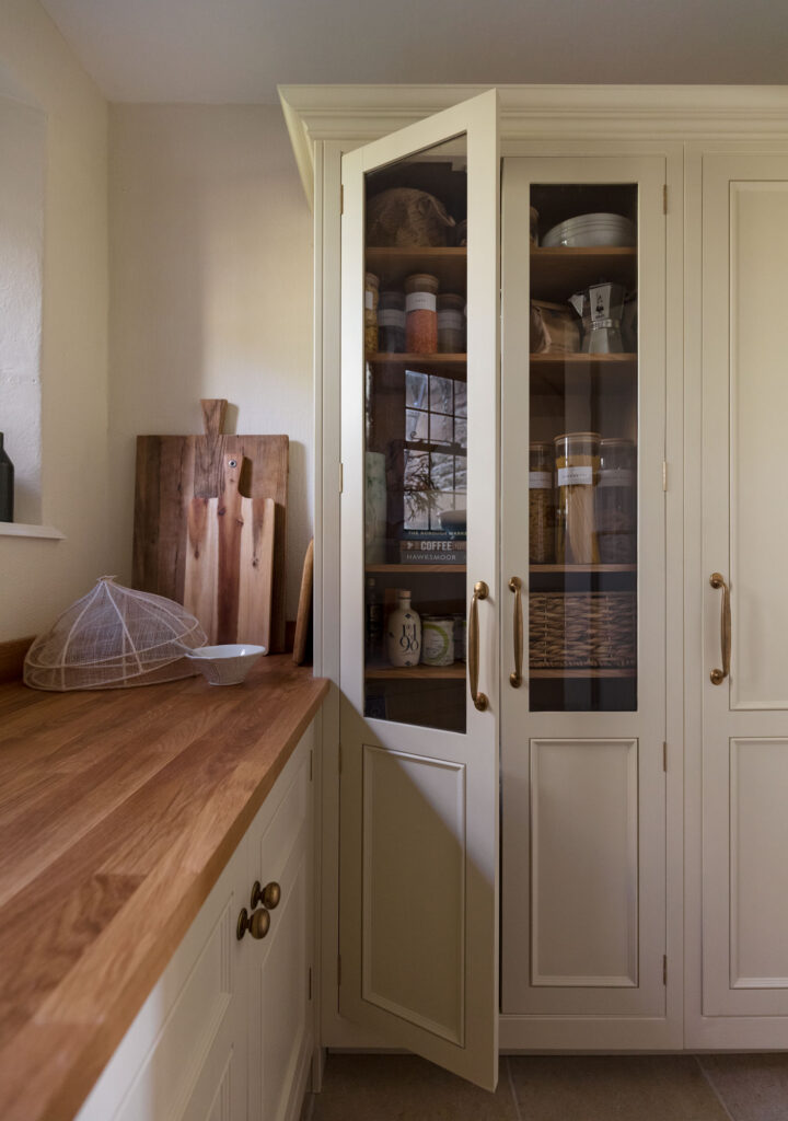 pantry with the door slightly open, pantry is filled with jars for pasta and oil