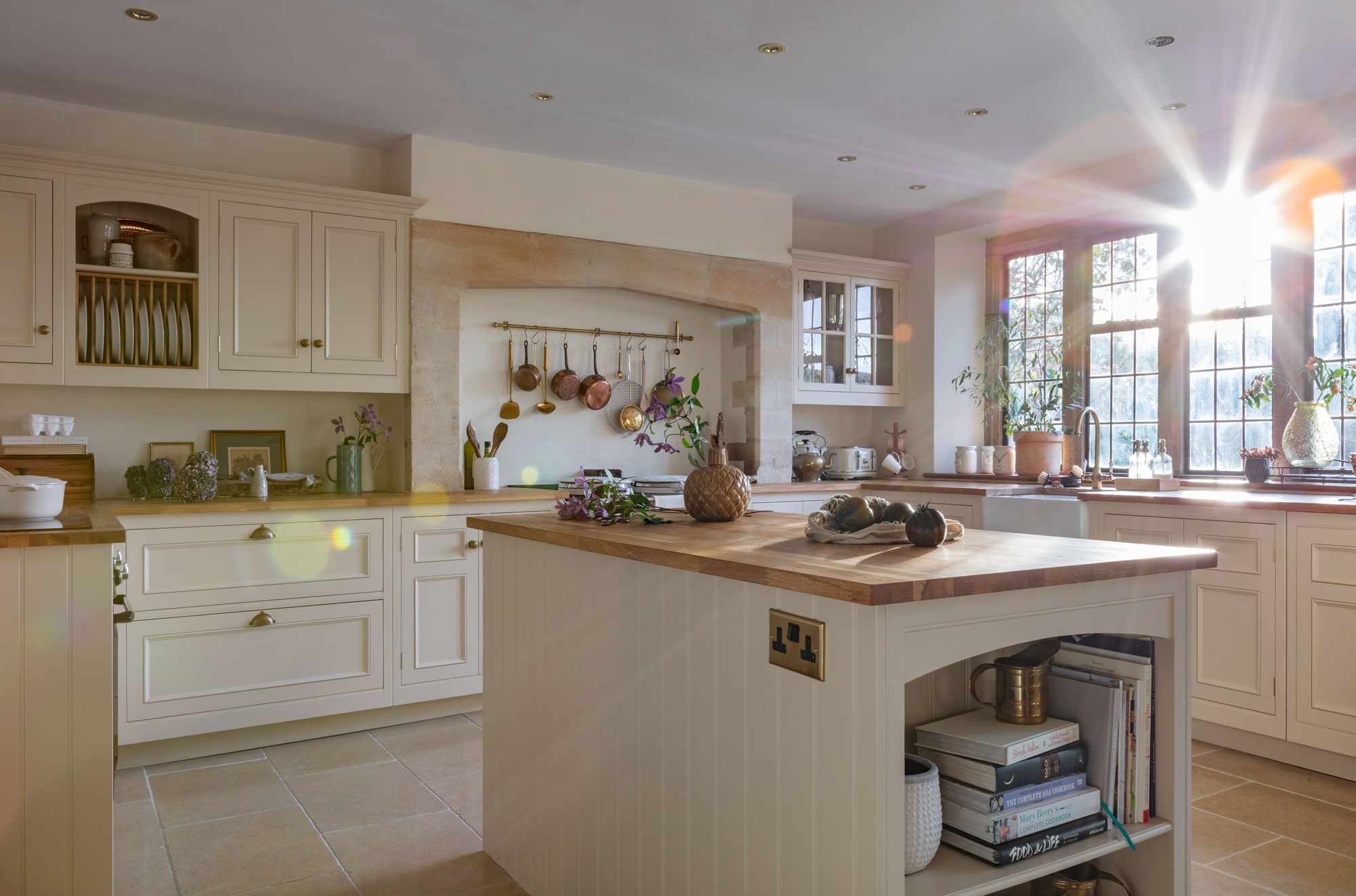 kitchen with units on the far rear walls and a kitchen island in the middle, there is a window at the back of the image with sun coming in from the right hand side