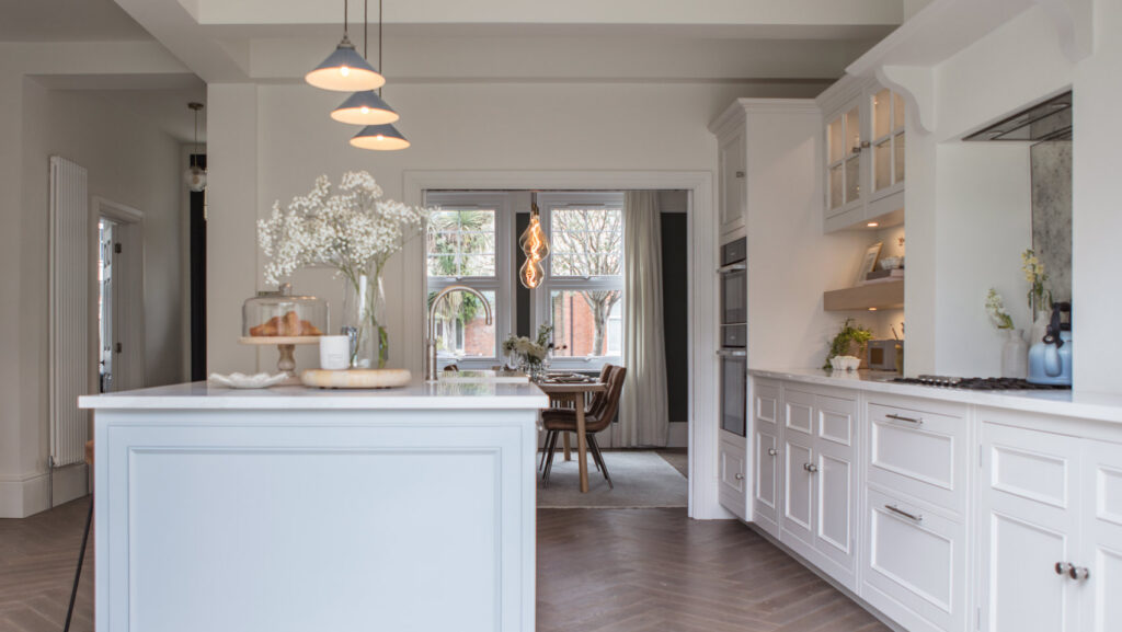 white kitchens units on the right hand side with a large kitchen island on the left - complete with quooker boiling tap