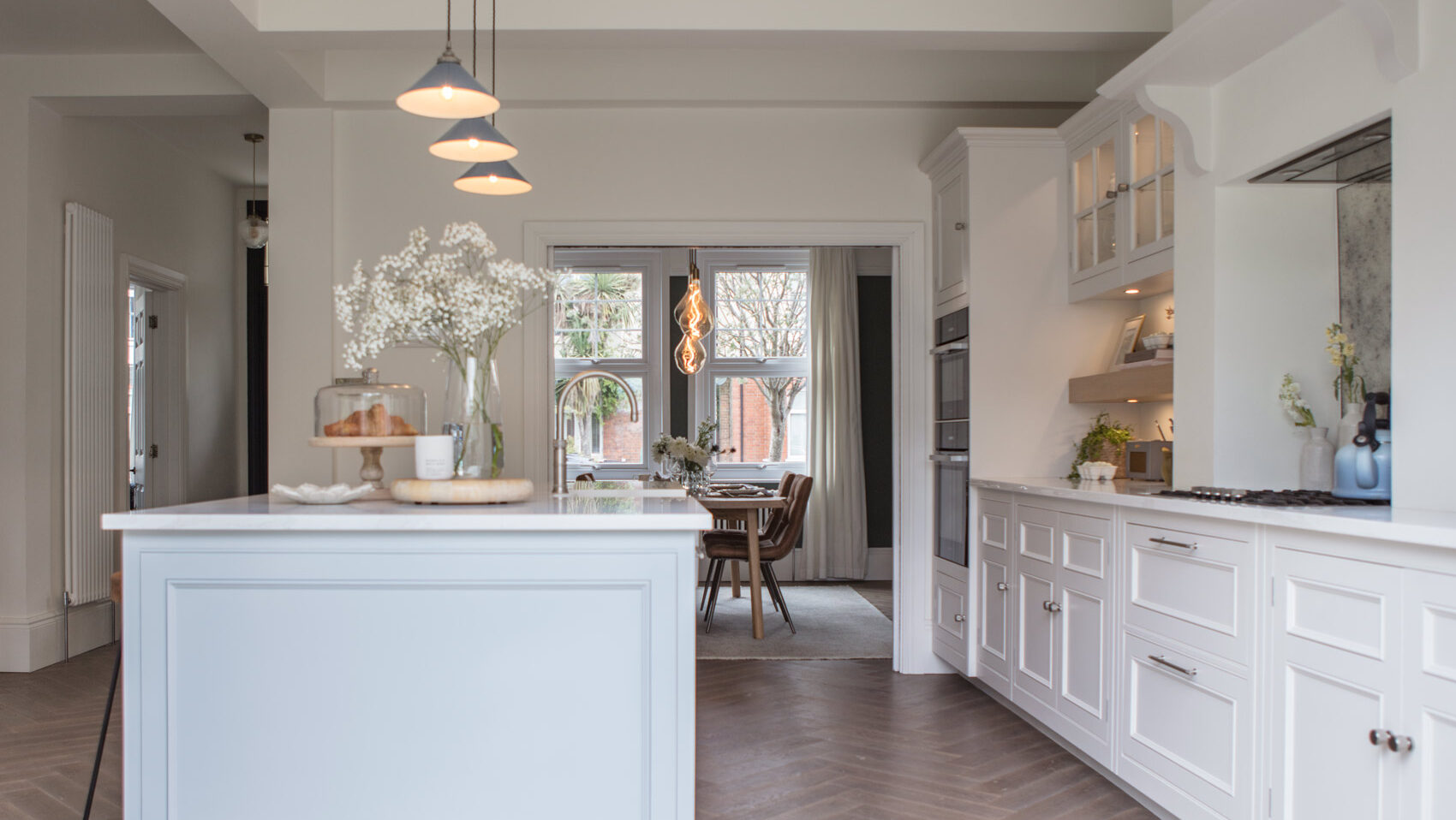 white kitchens units on the right hand side with a large kitchen island on the left - complete with quooker boiling tap