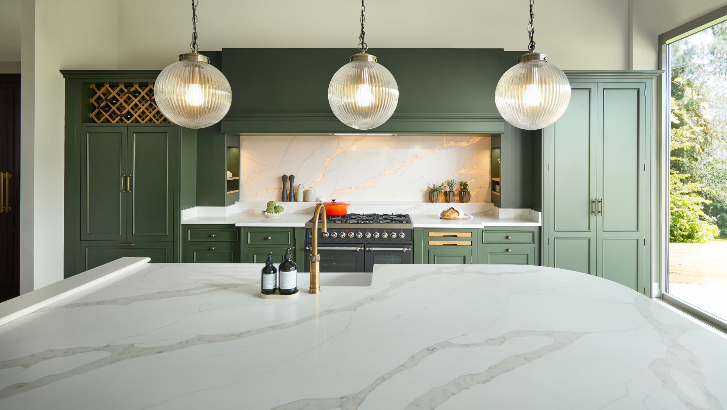 Green Kitchen with pendant lights sweeping over the island