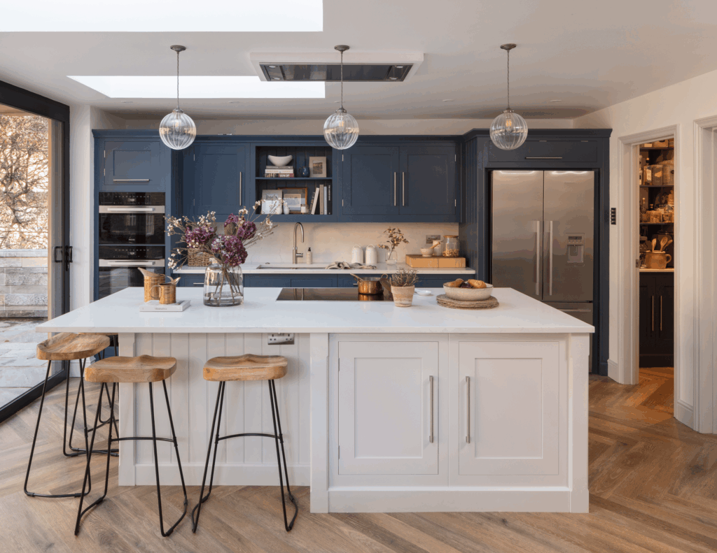 White kitchen island in blue shaker kitchen with walk-in pantry