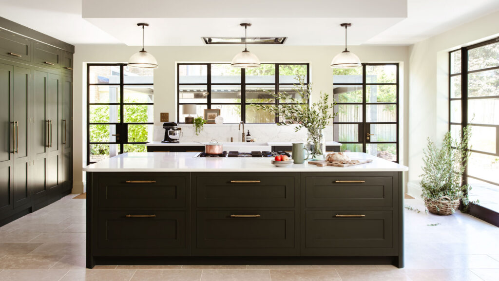 Large kitchen island in green shaker kitchen with crittall doors and windows