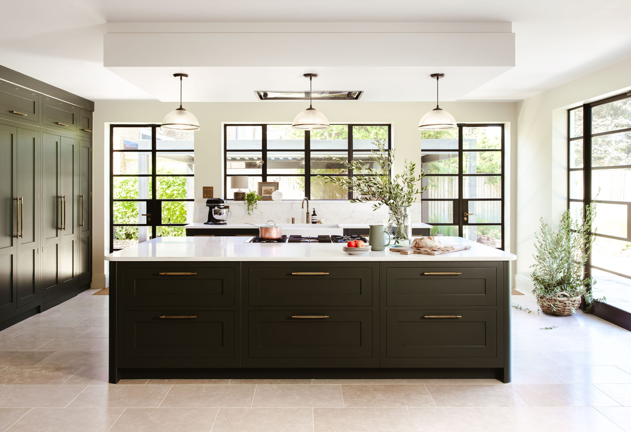 Large kitchen island in green shaker kitchen with crittall doors and windows