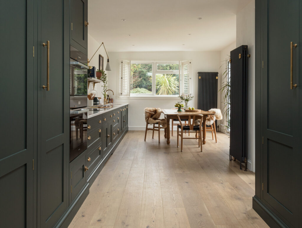 Green gallery kitchen with shaker cabinetry and dining table