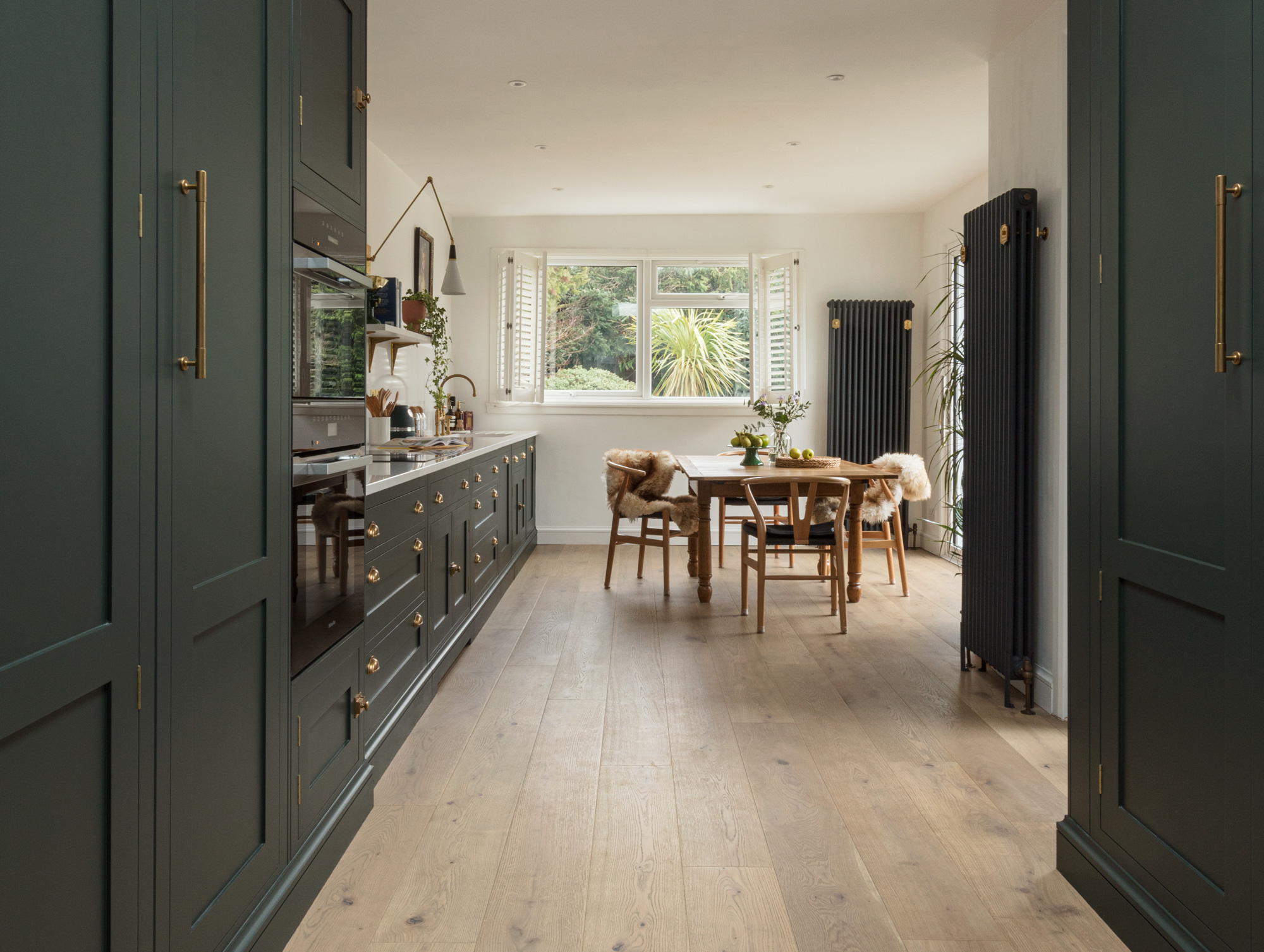 Green gallery kitchen with shaker cabinetry and dining table