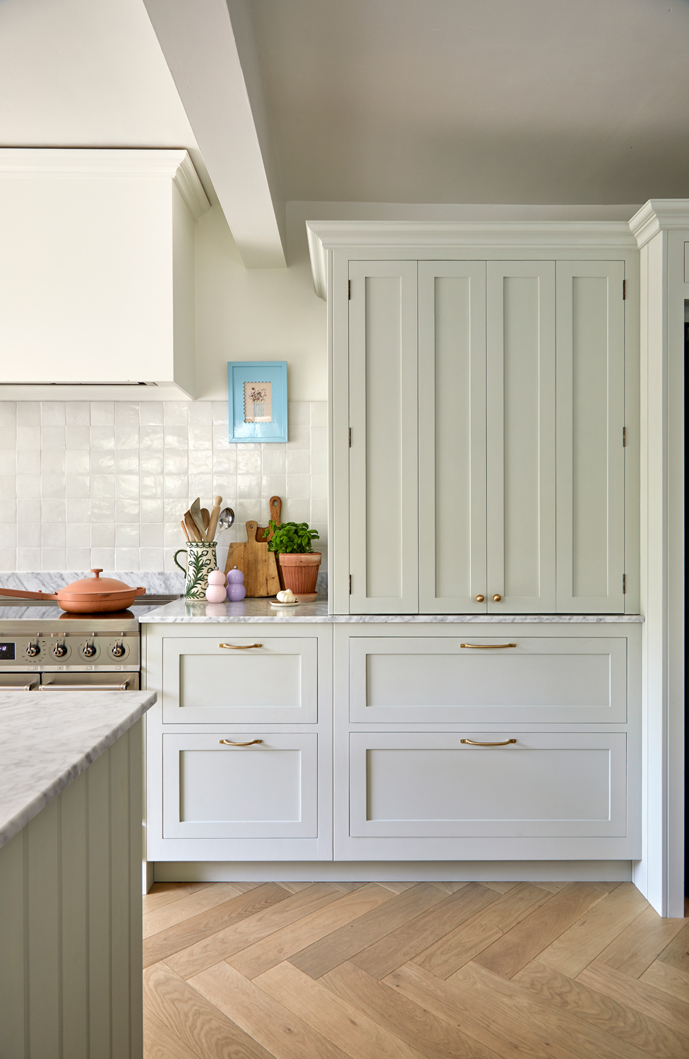 A luxury sage green kitchen, hidden kitchen storage displays seamless integration, with elegantly concealed storage compartments. White cabinets and gold accents provide a sleek touch, while the countertops light beige complements them perfectly. The well-thought-out design adds a hint of sophistication and functionality, creating a space that seamlessly blends modernity and tradition.