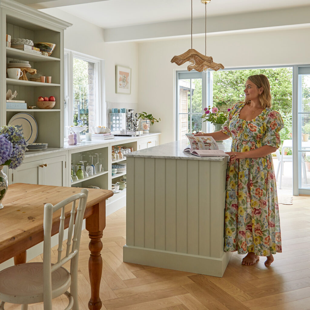 sage green kitchen with woman in floral dress