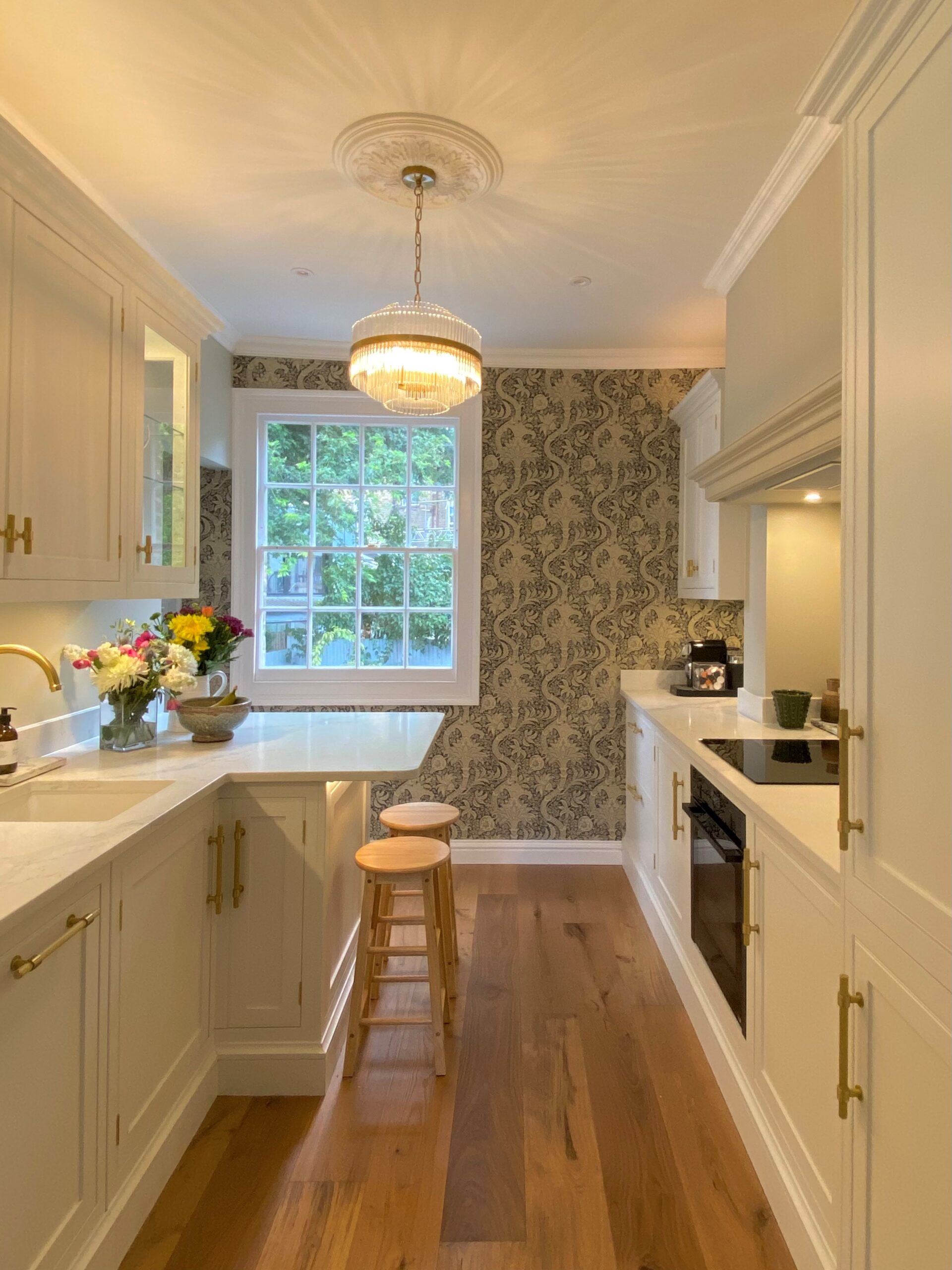 Compact kitchen design with sleek white cabinets and natural wooden floors, creating a stylish and functional space.