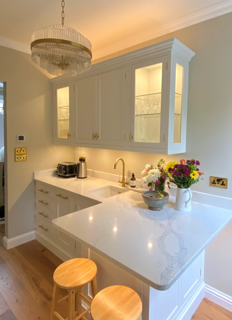 A small kitchen showcasing white cabinets, a countertop, and elegant glass cabinets, creating a clean and open atmosphere.