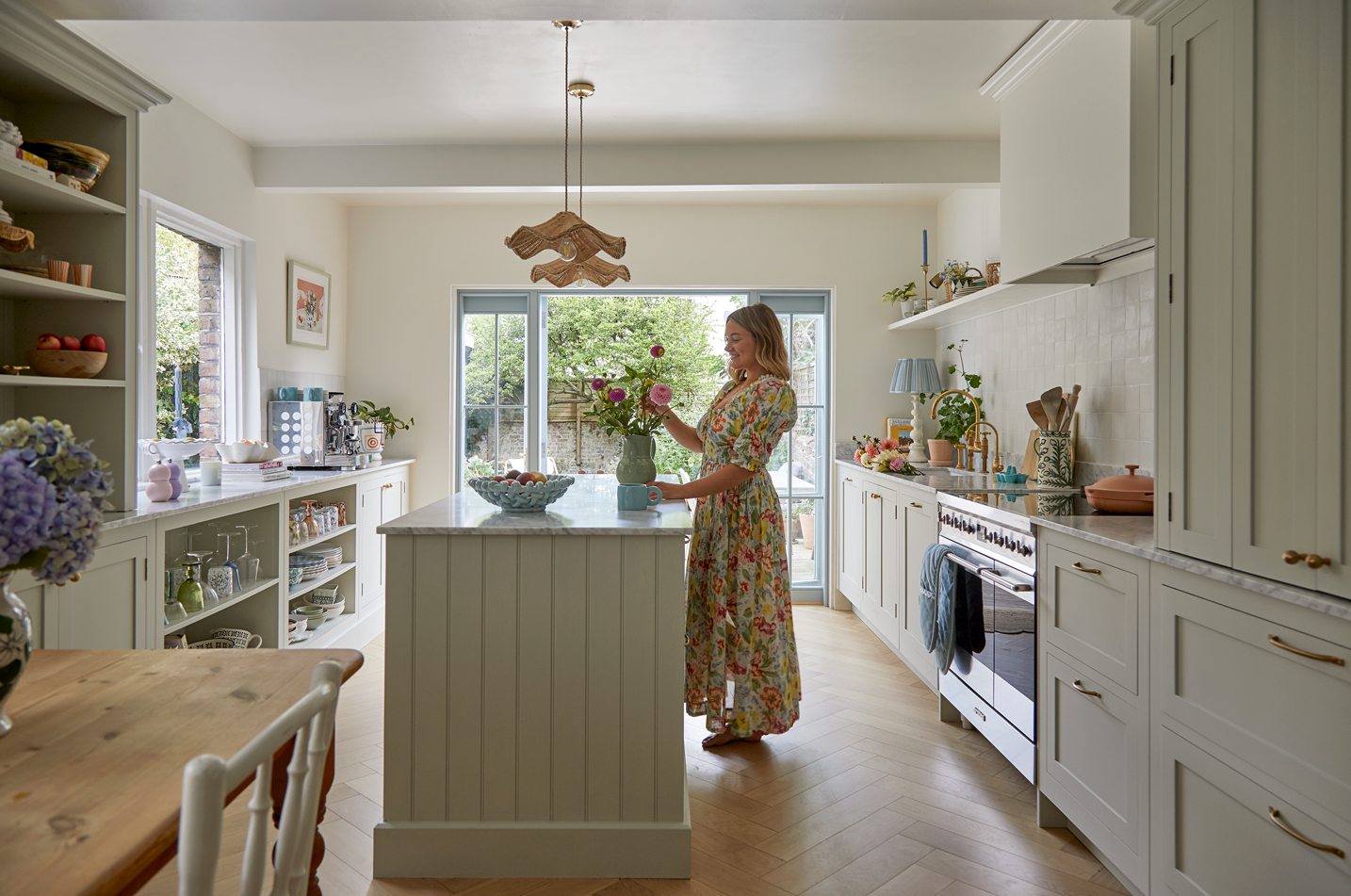 Light green Shaker kitchen with panelled island and modern cottage style with dining table for entertaining guests