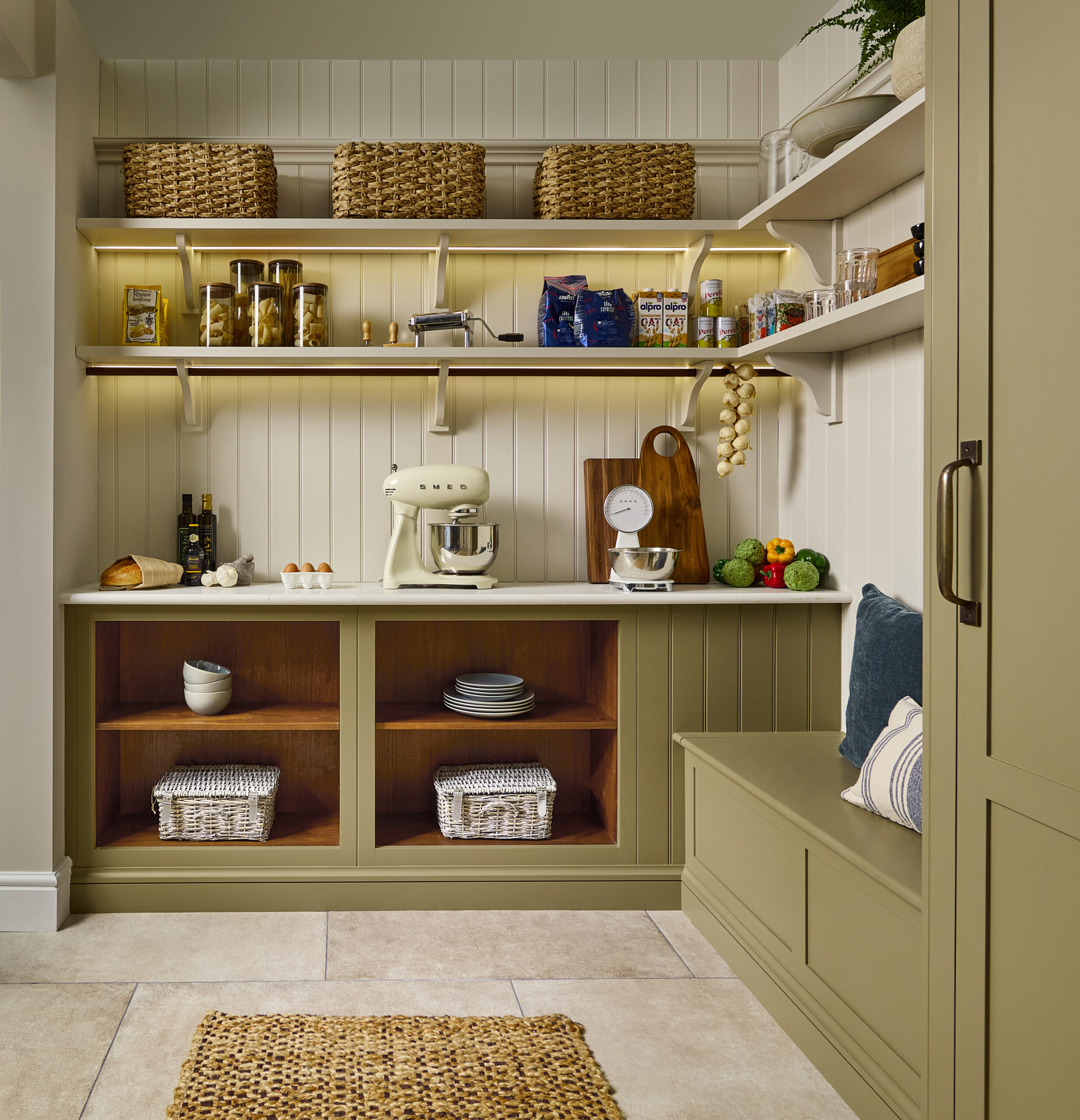 Green walk-in pantry and boot room with open shelving, hidden storage, and bench seating.