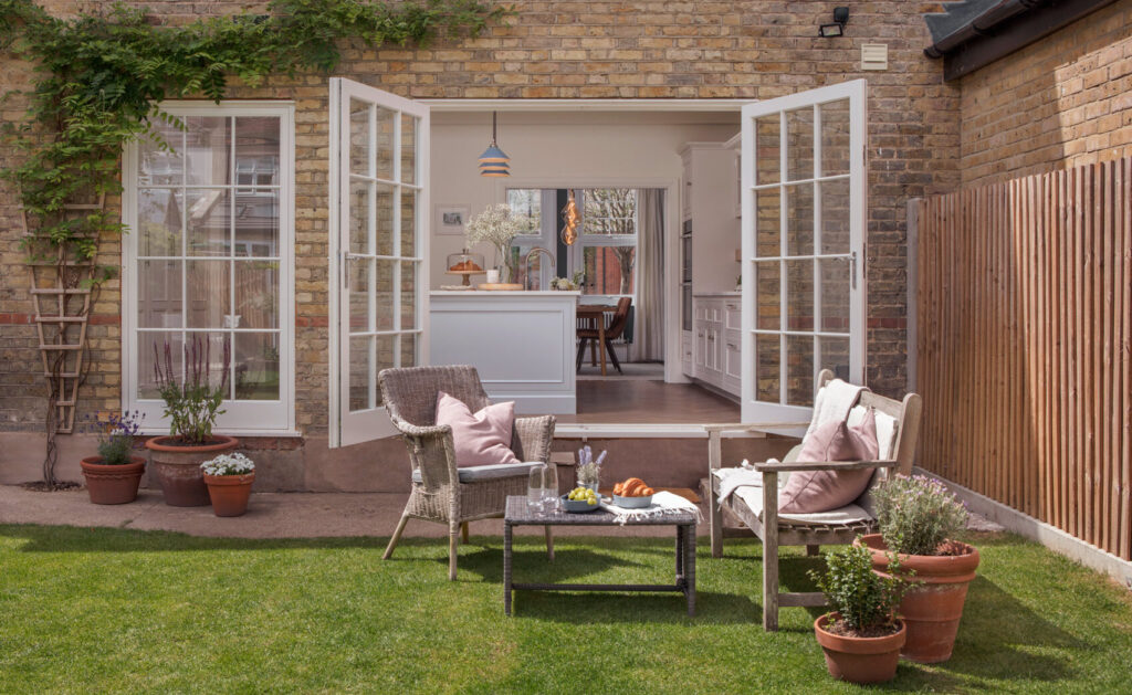 Indoor outdoor kitchen with french doors and open plan layout with island in a modern neutral kitchen design