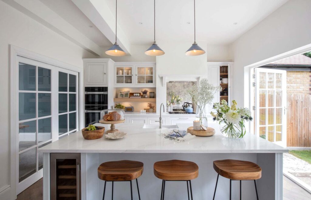 Light and open luxury kitchen showcasing tailored storage, marble worktops, and sophisticated design elements.