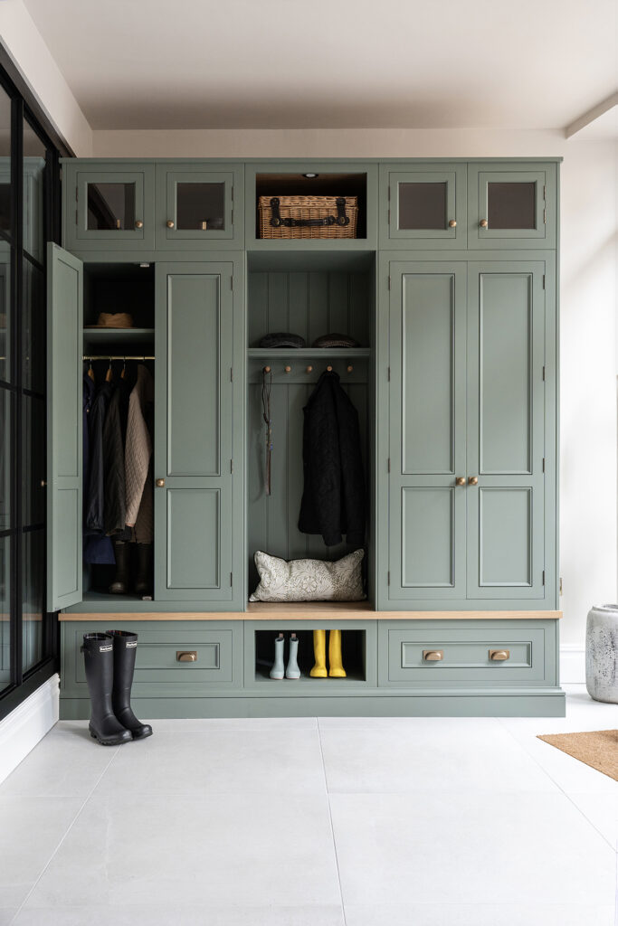 Luxury boot room with dedicated shoe storage, tall coat cupboards, and glass-fronted cabinets.