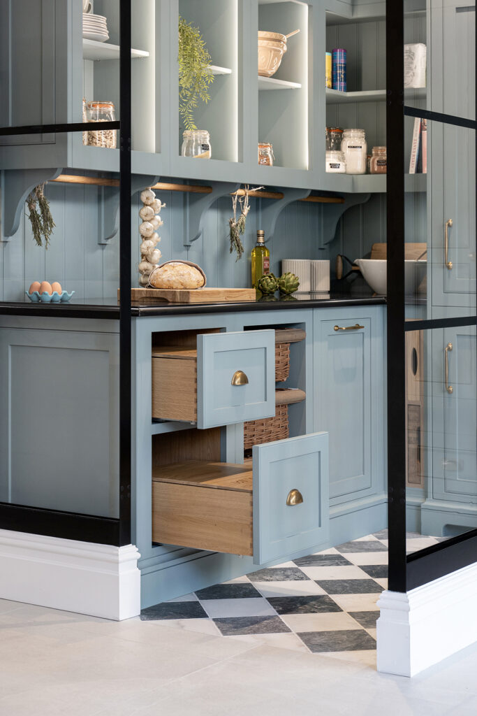 Walk-in pantry finished in blue, with solid wood drawer storage for pantry supplies and a hidden fridge.