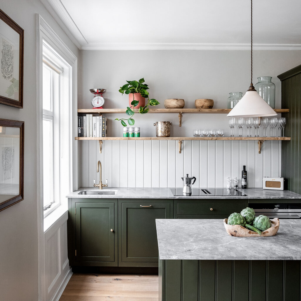 Green kitchen cabinetry with luxury marble countertops and open shelving