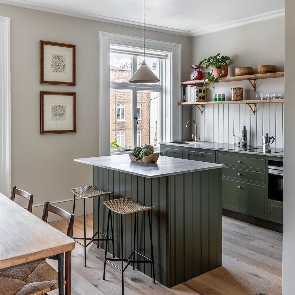 Luxury kitchen with green cabinetry and panelled island with seating