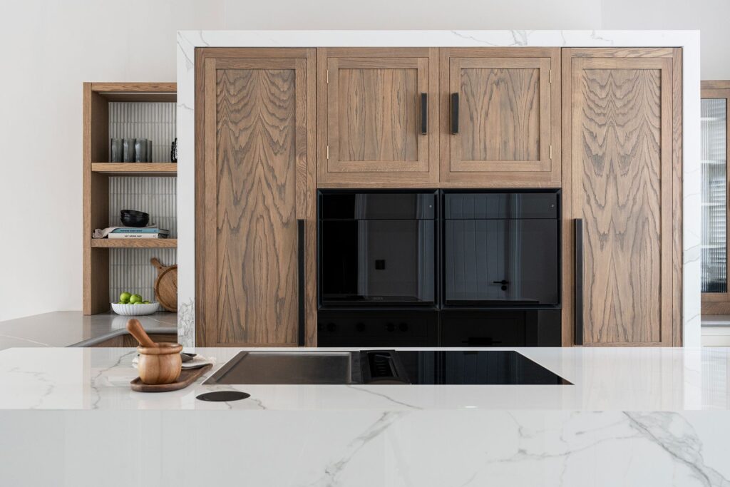 Shaker kitchen island with flush hob and marble worktop and dark wood cabinetry feature