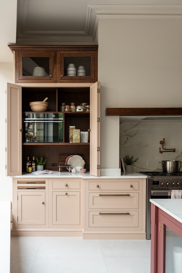 Open pink breakfast dresser with walnut interior in a luxury kitchen design.