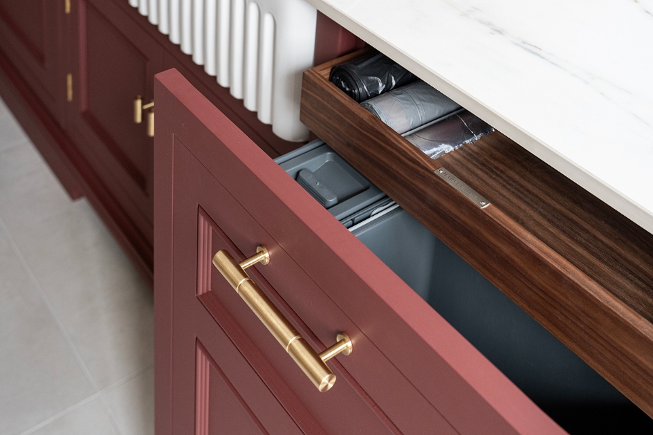 Burgundy kitchen drawer with walnut organiser and brass handle.