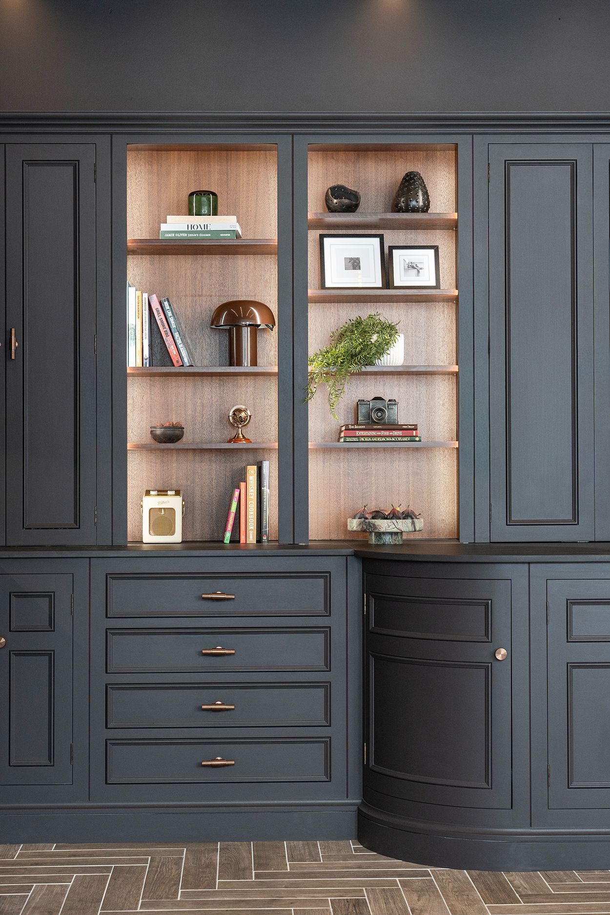 Bespoke dark kitchen cabinetry with curved detailing and walnut-toned shelving.