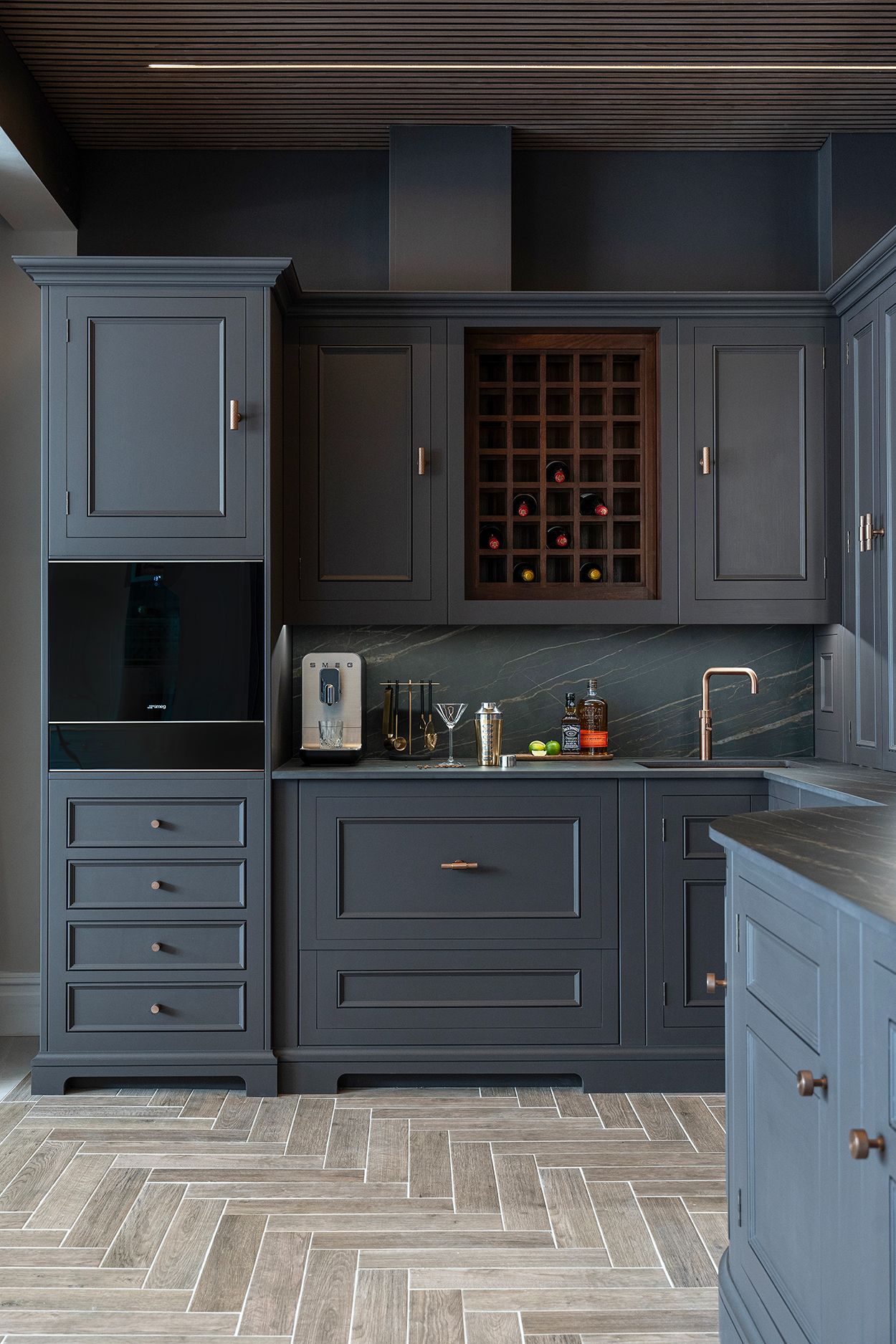 Dark bespoke kitchen cabinetry with integrated storage, wine rack, and copper fixtures.