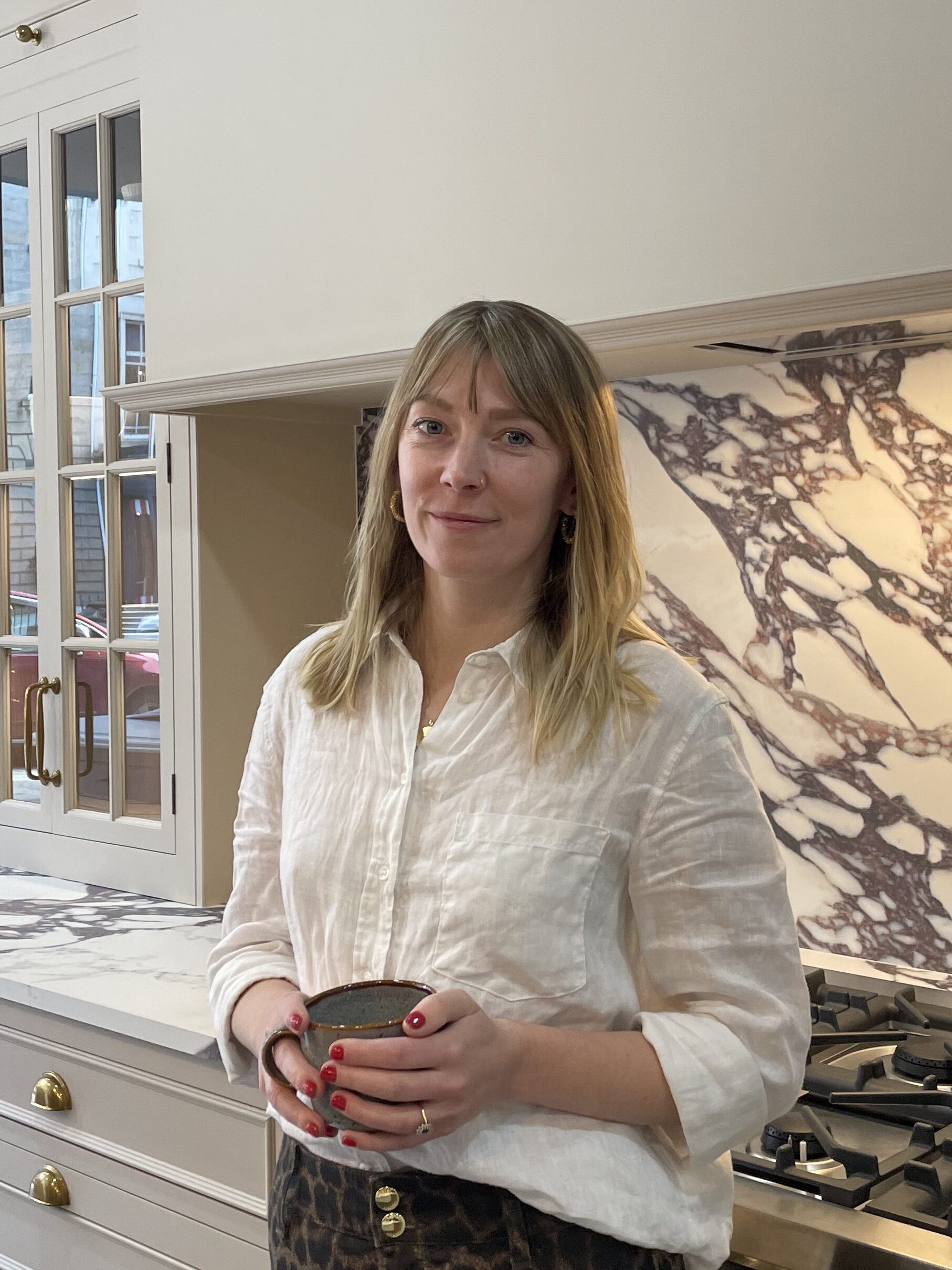 woman standing in front of calacatta marble holding a cup