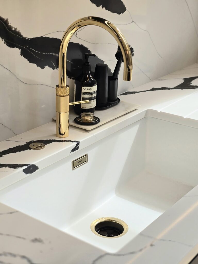 Marble countertop and white sink with gold hardware in a luxury bespoke kitchen
