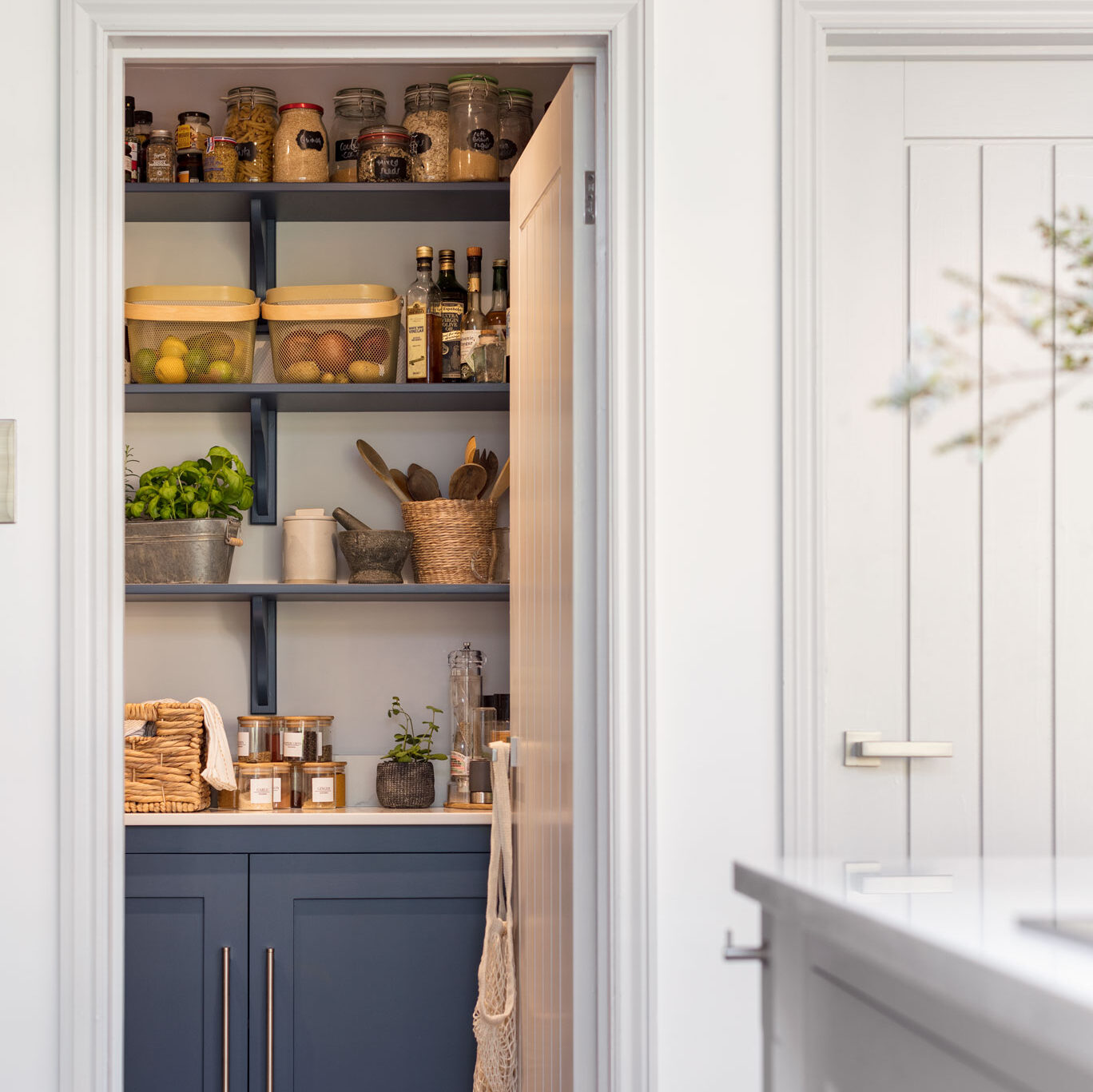 Hidden walk in pantry for bespoke kitchen living featuring navy blue cabinetry and open shelving