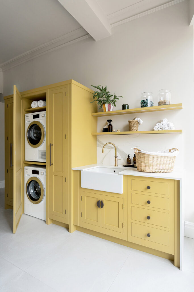 Yellow utility room with stacked washer and dryer, and counter space with open shelving