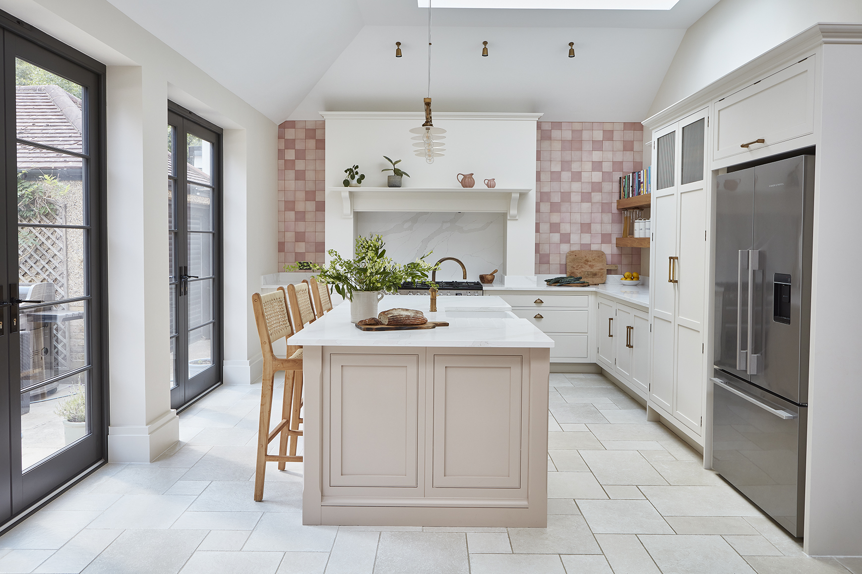 Open plan bespoke kitchen design with pink tiles and airy feel