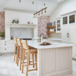Soft pink kitchen design with wooden island seating and tall skylight