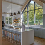 Bright light blue Shaker kitchen with island, natural wood details and gable end window.