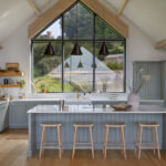 Light blue Shaker kitchen island with white quartz worktop and integrated seating.
