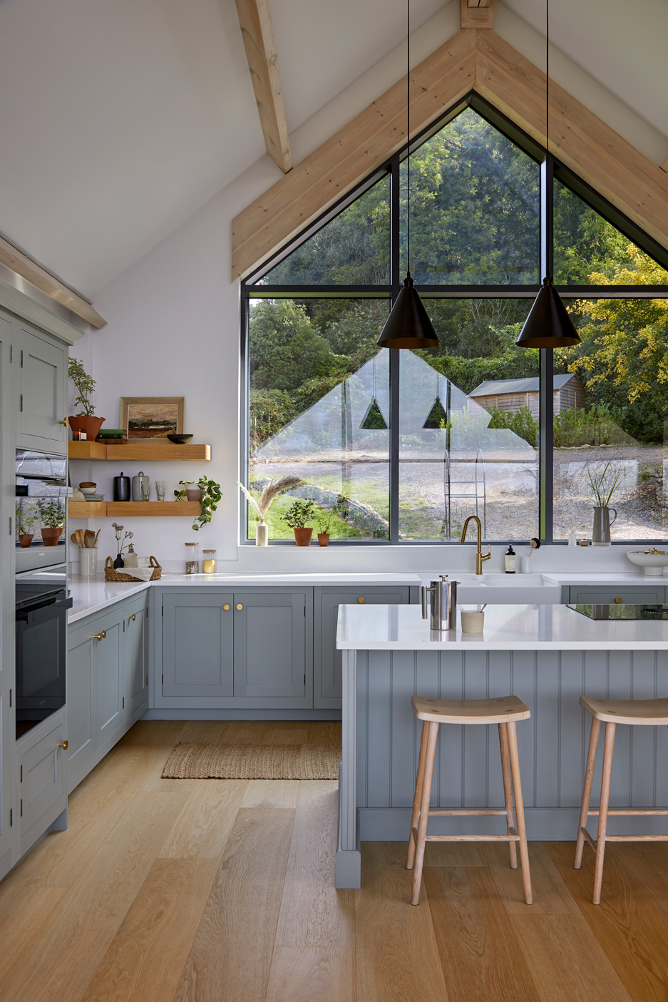 Panelled island seating in a blue Shaker kitchen with light wood stools.