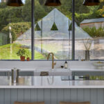 Brass kitchen tap and sink positioned beneath a gable end window in a luxury bespoke kitchen