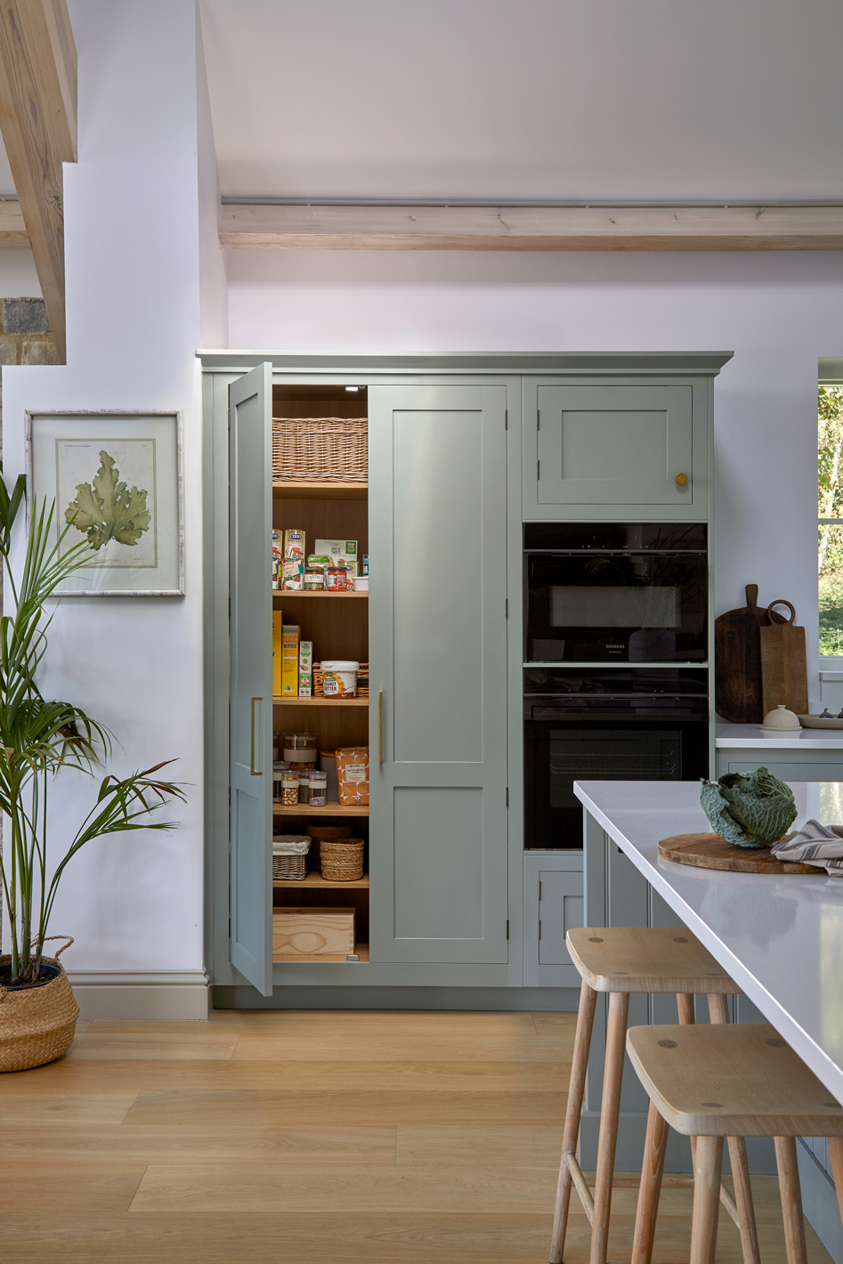 Tall pantry cabinets offering bespoke storage in a blue Shaker kitchen