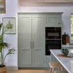 Integrated double ovens within tall blue Shaker kitchen cabinetry