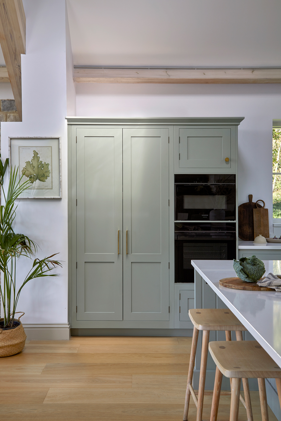 Integrated double ovens within tall blue Shaker kitchen cabinetry