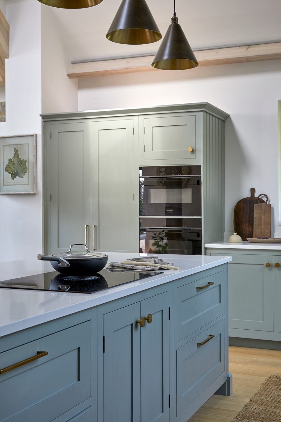 Integrated double ovens within tall Shaker cabinetry in a light blue kitchen